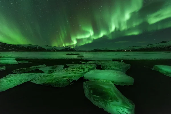 En vacker grön och röd aurora dansa över Glaciärlagunen lagunen, Island Royaltyfria Stockfoton