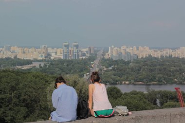 İki kız, Ukrayna 'nın Kiev şehrinin panorama manzaralı dağında sırtüstü oturuyor.