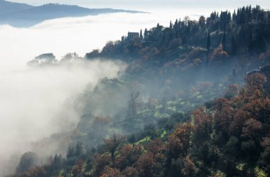 Güzel Tuscany tepeleri sisli sabah manzarası yaylaları ve tarlaları kaplayan ışığın sihirli bir ışık gölgesi gradyanı oluşturduğu yer.