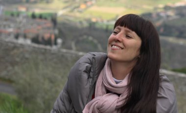 Bulanık, ilkbahar, yeşil Toskana manzarasının arka planında yürüyen gülümseyen bir kadının portresi. 