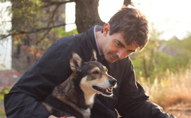 Güneşli bir günbatımının bulanık ışınlarıyla çevrili, sahibinin yanında oturan köpeğin mutlu ağızlık sesi. 