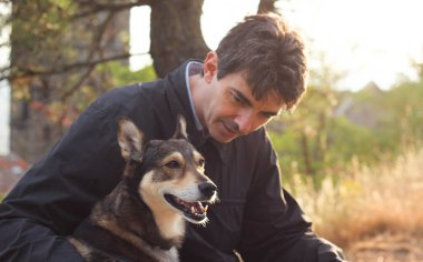 Güneşli bir günbatımının bulanık ışınlarıyla çevrili, sahibinin yanında oturan köpeğin mutlu ağızlık sesi. 