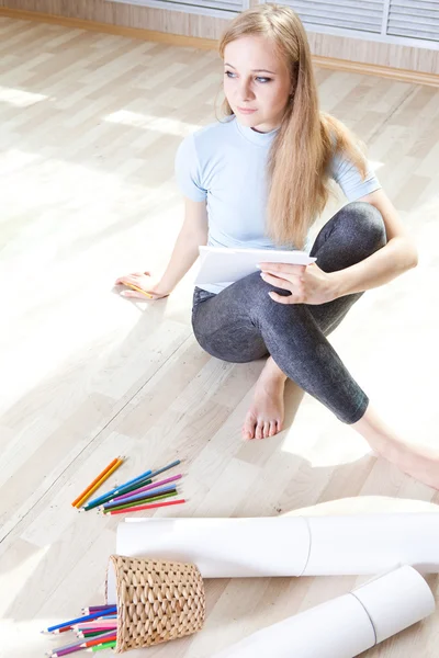 Junges Teenager-Mädchen auf dem Boden denkt und zeichnet — Stockfoto