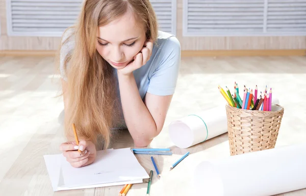 Junges Teenager-Mädchen auf dem Boden denkt und zeichnet — Stockfoto