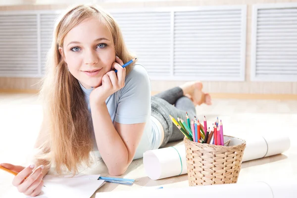 Junges Teenager-Mädchen auf dem Boden denkt und zeichnet — Stockfoto