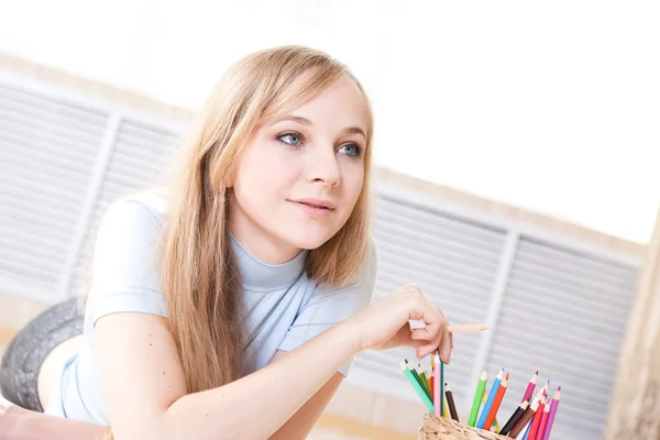 Junges Teenager-Mädchen auf dem Boden denkt und zeichnet — Stockfoto