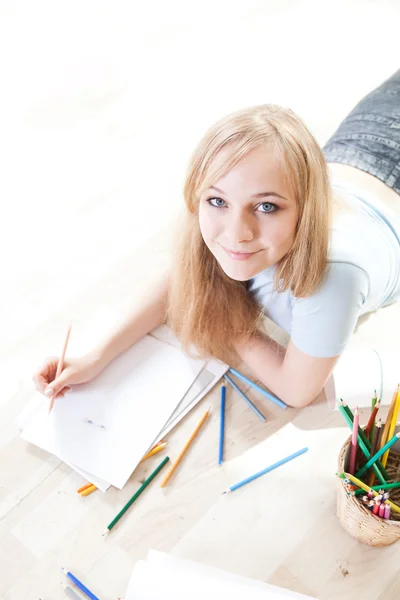 Ung teenage pige på gulvet tænker og tegner - Stock-foto