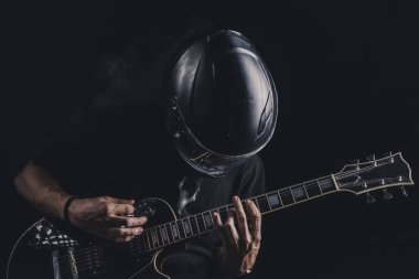 Motosiklet kasklı bir adam arka planda elektro gitar çalıyor.