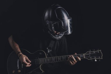 Motosiklet kasklı bir adam arka planda elektro gitar çalıyor.