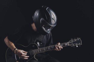 Motosiklet kasklı bir adam arka planda elektro gitar çalıyor.