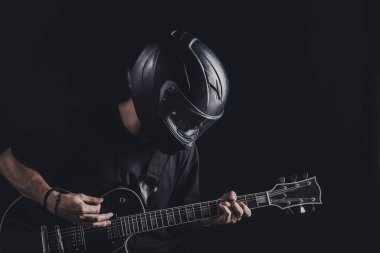 Motosiklet kasklı bir adam arka planda elektro gitar çalıyor.