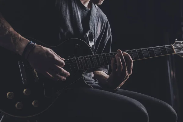 Guy in a T-shirt plays an electric guitar on a dark background