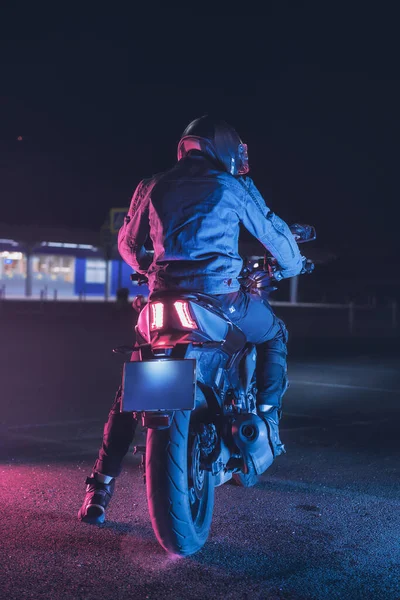 Motociclista Senta Uma Moto Luz Néon Estacionamento Vazio Noite — Fotografia de Stock