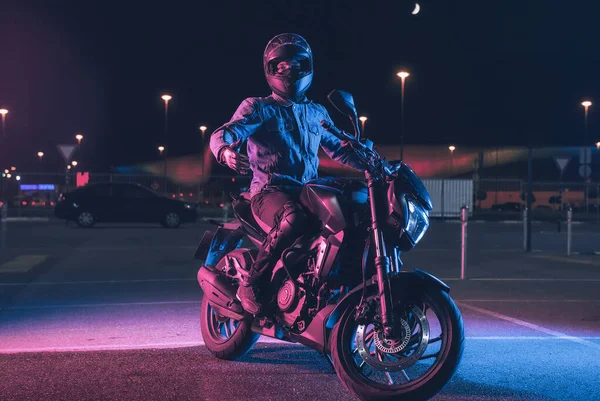 Motociclista Senta Uma Moto Luz Néon Estacionamento Vazio Noite — Fotografia de Stock