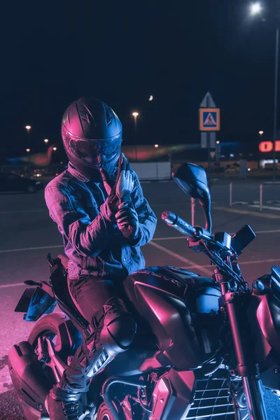 自転車愛好家は夜の駐車場でネオンライトのバイクに座っています — ストック写真