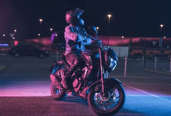 Motorcyclist Κάθεται Μια Μοτοσικλέτα Νέον Φως Ένα Άδειο Χώρο Στάθμευσης Royalty Free Φωτογραφίες Αρχείου