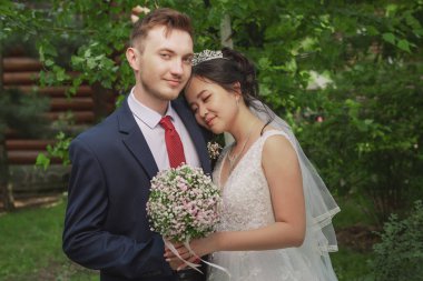 Uluslar arası bir çiftin portresi. Doğanın ve çiçeklerin arka planına karşı yeni evliler.