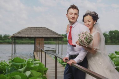 Uluslar arası bir çiftin portresi. Doğanın ve çiçeklerin arka planına karşı yeni evliler.