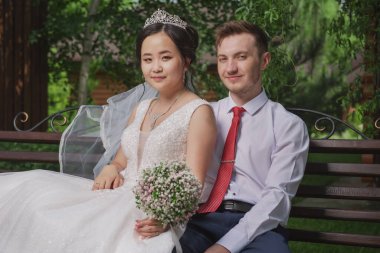 Uluslar arası bir çiftin portresi. Doğanın ve çiçeklerin arka planına karşı yeni evliler.