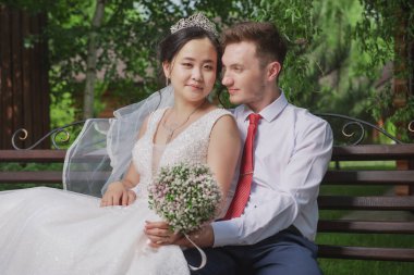 Uluslar arası bir çiftin portresi. Doğanın ve çiçeklerin arka planına karşı yeni evliler.