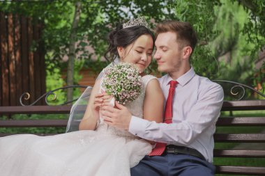 Uluslar arası bir çiftin portresi. Doğanın ve çiçeklerin arka planına karşı yeni evliler.