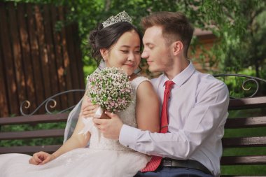 Uluslar arası bir çiftin portresi. Doğanın ve çiçeklerin arka planına karşı yeni evliler.