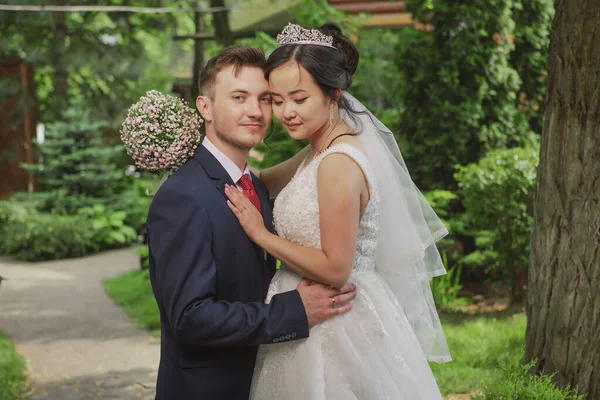 Portrait of an international loving couple of newlyweds against the backdrop of nature and flowers