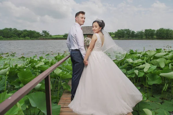 Portrait of an international loving couple of newlyweds against the backdrop of nature and flowers