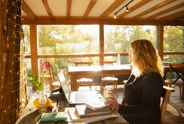 Güneşli Restoranda Dizüstü Bilgisayarda Çalışan Düşünceli Bir Kadını — Stok fotoğraf
