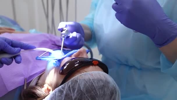 Zubař léčí zuby ženě na klinice. Ženský profesionální lékař stomatolog Zubař vezme nástroj. Zubní zařízení na pozadí. 
