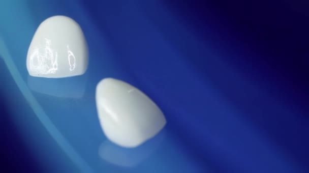 黑色背景上的陶瓷假牙和牙冠 一组单一的假牙和牙冠的顶部视图 隔离黑色背景下的锆冠和锆混合压榨机 — 图库视频影像