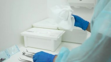Sağlık çalışanı diş hekimliğinde temizlik temizleme aletleri hazırlıyor. Diş kliniği asistanı stomatolojik aletleri fırça ve sterilizasyon ile yıkıyor. Salgın sırasında yakın çekim koruma