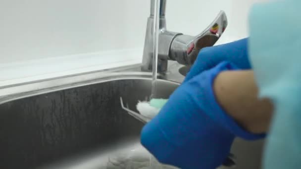 Очистка, стерилизация и дезинфекция медицинских инструментов в стоматологии. Ассистент стоматолога стирает инструменты стоматолога щеткой под проточной водой из крана. Защита крупным планом во время пандемии — стоковое видео