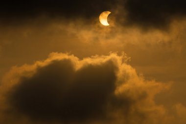 The Moon covering the Sun in a partial eclipse with dramatic cloud. Scientific background, astronomical phenomenon. clipart