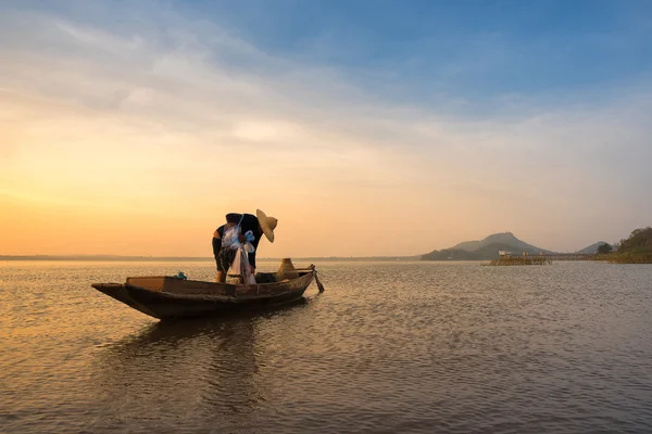 Ασιατικές ψαράς στο ξύλινο σκάφος προετοιμασία ένα δίχτυ για αλίευση ψαριών του γλυκού νερού στον ποταμό φύση νωρίς το πρωί πριν από την Ανατολή — Φωτογραφία Αρχείου