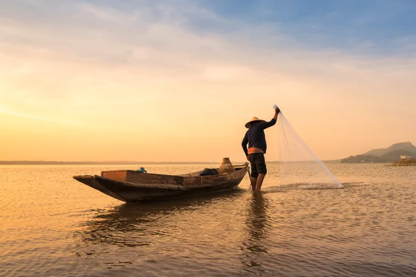 Pêcheur asiatique jetant un filet pour attraper des poissons d'eau douce dans la rivière de la nature tôt le matin avant le lever du soleil — Photo