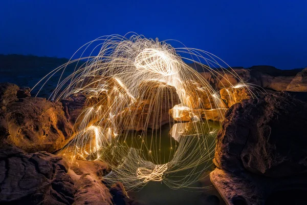 Captura de larga exposición de lana de acero ardiente girada antes del atardecer en un gran campo de roca de cañón de Tailandia —  Fotos de Stock