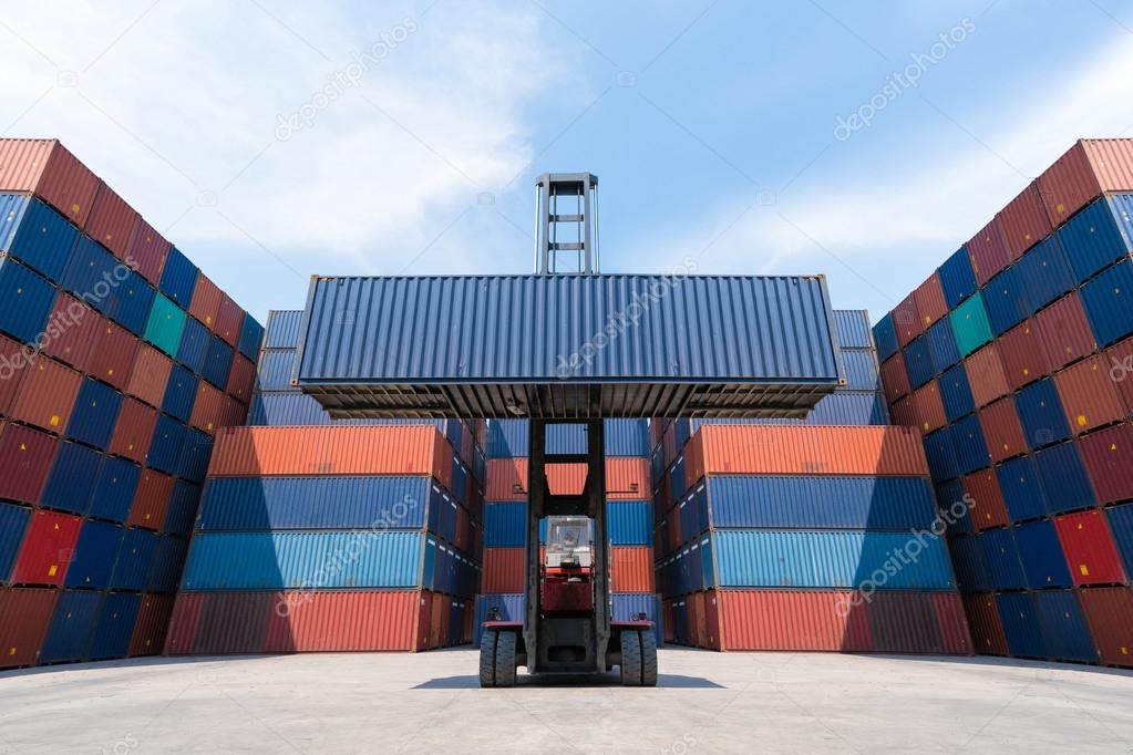 Forklift truck lifting cargo container in shipping yard for import,export, logistic industrial with container stack background