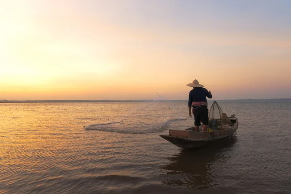 Pescador asiático con su barco de madera va a la captura de peces de agua dulce en el río naturaleza en la madrugada durante el amanecer —  Fotos de Stock