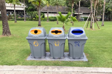 Parkta farklı atık ürünleri ayırmak için üç plastik geri dönüşüm kutuları
