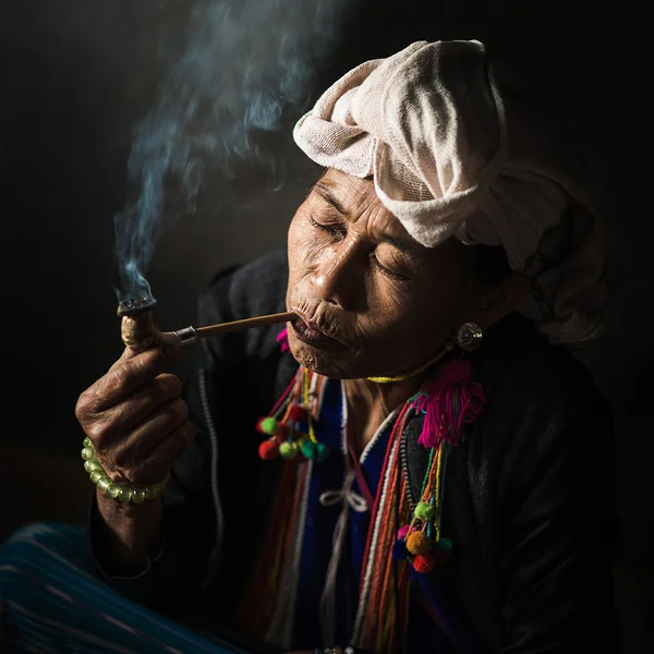 Karen hill tribe is smoking tobacco pipe with traditional clothes — ストック写真