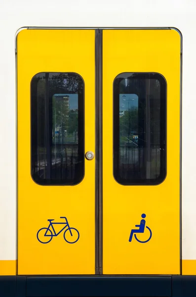 Detail of a yellow sliding door with bicycle and wheelchair symbol on a modern train. — 图库照片