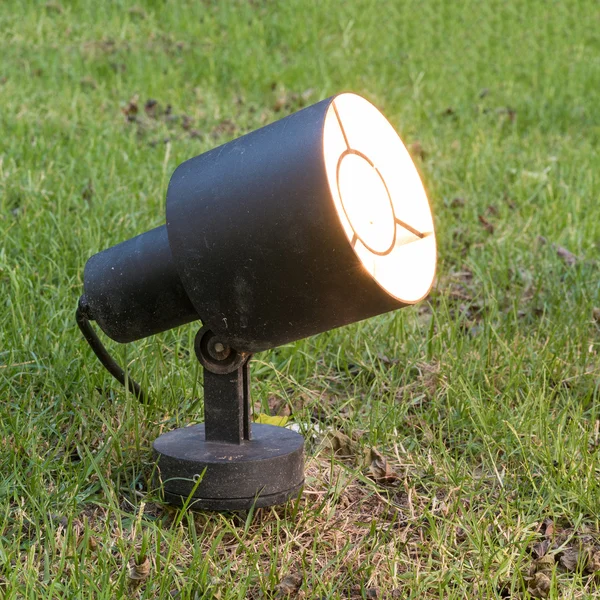 One garden ground lamp light up in a green garden among grass — Stockfoto