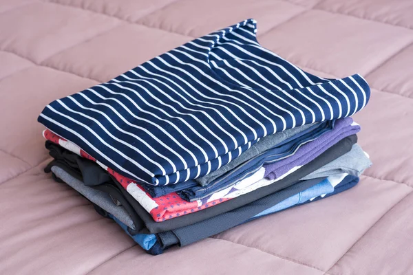 Складывание одежды на кровати перед хранением в шкафу — стоковое фото