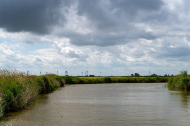 Friesland, Aşağı Saksonya, Almanya 'da mavi gökyüzünde dramatik bulutlar olan bir lağım manzarası
