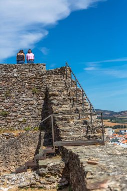 Mogadouro / Portekiz - 08 23 2020: Kale duvarında oturmuş manzaraya bakan iki genç kız...