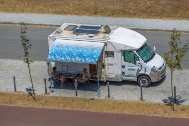 Regua / Portugal - 10 / 02 / 2020: Karavanın önünde kahve içen yaşlı bir çiftin yabancı turist kampında yolun kenarına park edilmiş görüntüsü...
