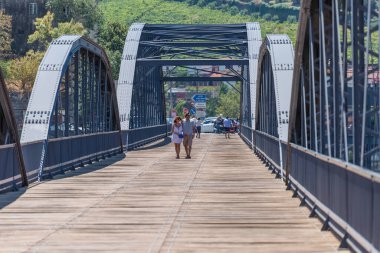 Regua / Portekiz - 10 / 02 / 2020: Regua kentinin metalik köprüsünde gezinen, sırtüstü kucaklaşan bir çift turisti görmek