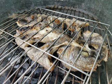 Yanan kömür ateşinde kızartılmış balıkların detaylı görüntüsü, sağlıklı ve tipik Akdeniz yemekleri....