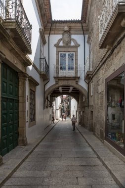Guimaraes / Portekiz - 12 09 2020: Guimaraes şehir merkezinde klasik binaları olan eski ve dar bir sokağa bakın, arka planda yürüyen bir çift